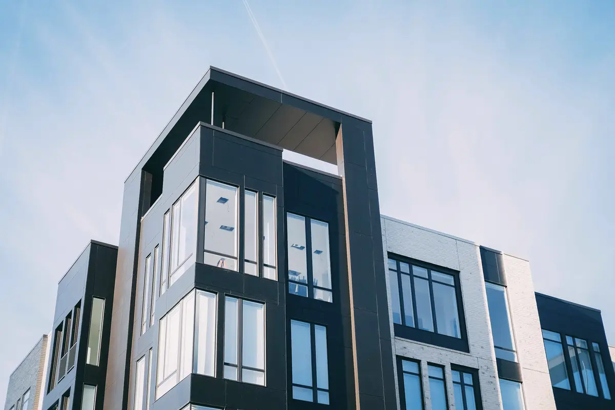 A contemporary black and white residential building seen from below against a pale sky