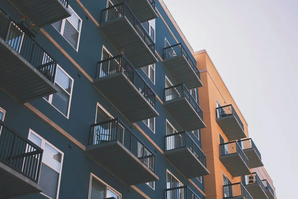 A low-angle view of an apartment building with dark blue and orange cladding and balconies