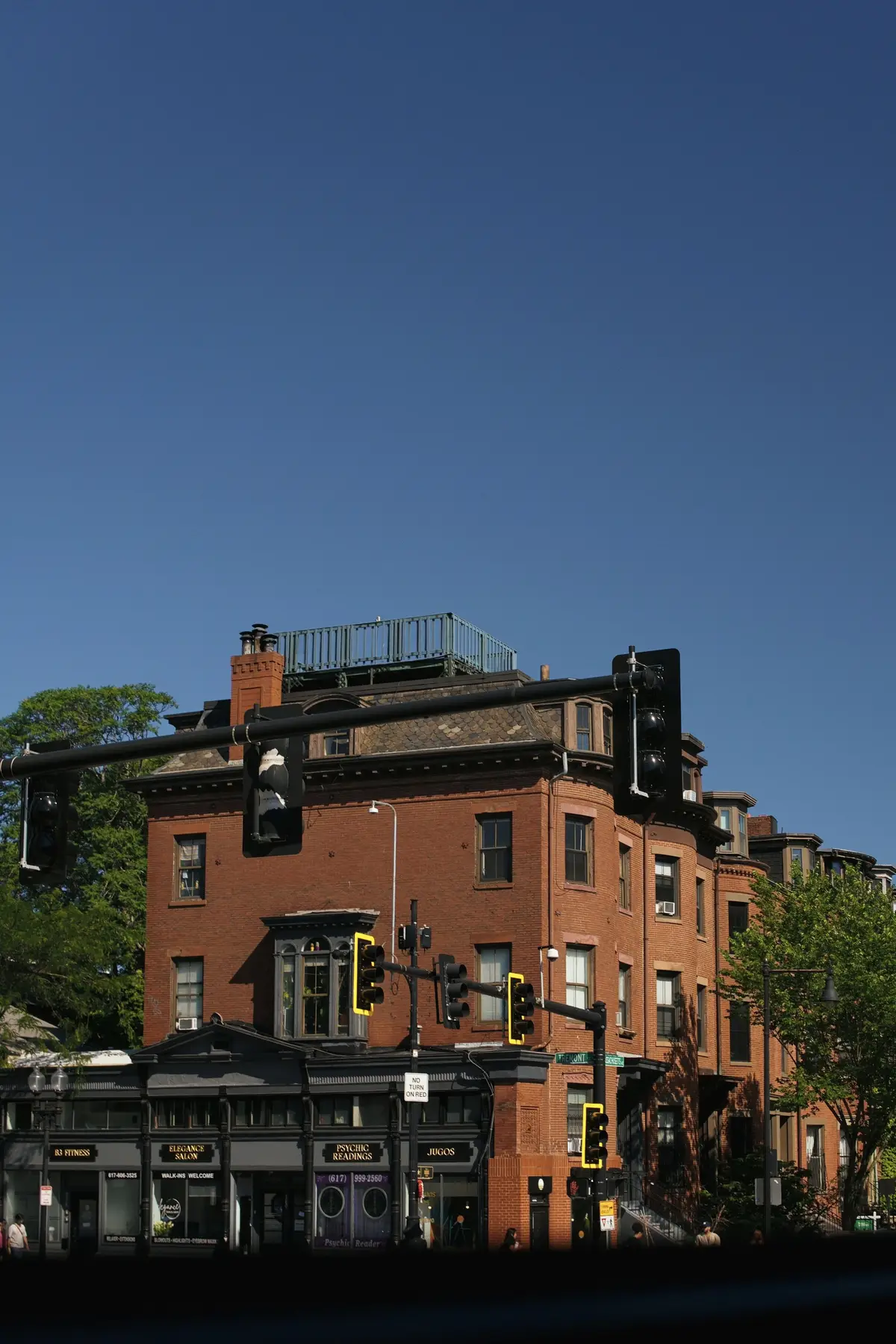A brick corner building with a traffic light under a clear sky