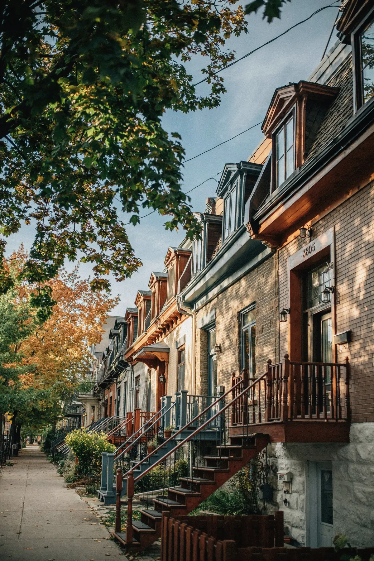 Brick plexes with exterior stairs and balconies on a tree-lined street in autumn